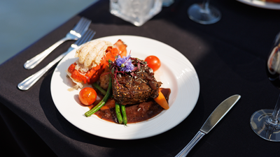 Assiette comprenant un repas bistronomique avec de la viande grillée, une queue de homard, accompagnés de légumes frais du marché