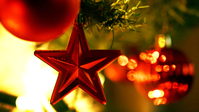 Un gros plan d'une étoile rouge suspendue à un sapin de Noël décoré de manière festive.