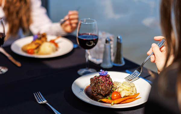 Assiette comprenant un repas bistronomique de viande grillée avec des légumes frais du marché accompagné d'un verre de vin rouge