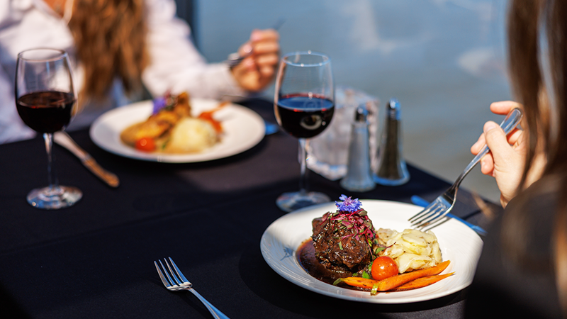 Assiette comprenant un repas bistronomique de viande grillée avec des légumes frais du marché accompagné d'un verre de vin rouge