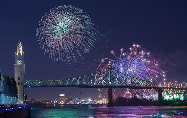 Vue sur la tour de l'horloge et le pont Jacques Cartier à Montréal avec des feux d'artifice majesteux surplombant les monuments