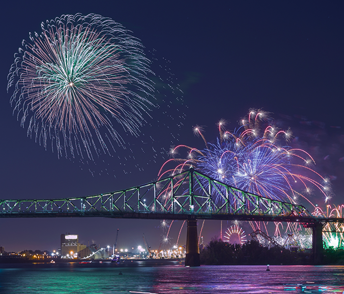 Vue sur la tour de l'horloge et le pont Jacques Cartier à Montréal avec des feux d'artifice majesteux surplombant les monuments