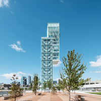 Tour du Port de Montréal avec en premier plan une esplanade arborée et en arrière plan des immeubles de Montréal