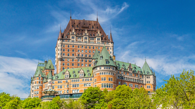 Le Château Frontenac de Québec se dressant majestueusement avec un ciel bleu et de la verdure luxuriante.