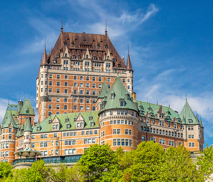 Le Château Frontenac de Québec se dressant majestueusement avec un ciel bleu et de la verdure luxuriante.