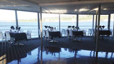 Salle intérieure avec des tables dressées devant une fenêtre donnant vue sur le fleuve Saint-Laurent à Québec
