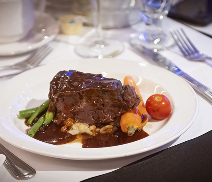 Une assiette comprenant un succulent plat de bœuf, garni de haricots verts, d'une tomate rôtie et d'un accompagnement de pommes de terre en gros plan.