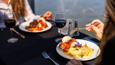 Plate containing a bistronomic meal of grilled meat with fresh market vegetables accompanied by a glass of red wine