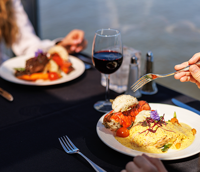 Plate containing a bistronomic meal of grilled meat with fresh market vegetables accompanied by a glass of red wine