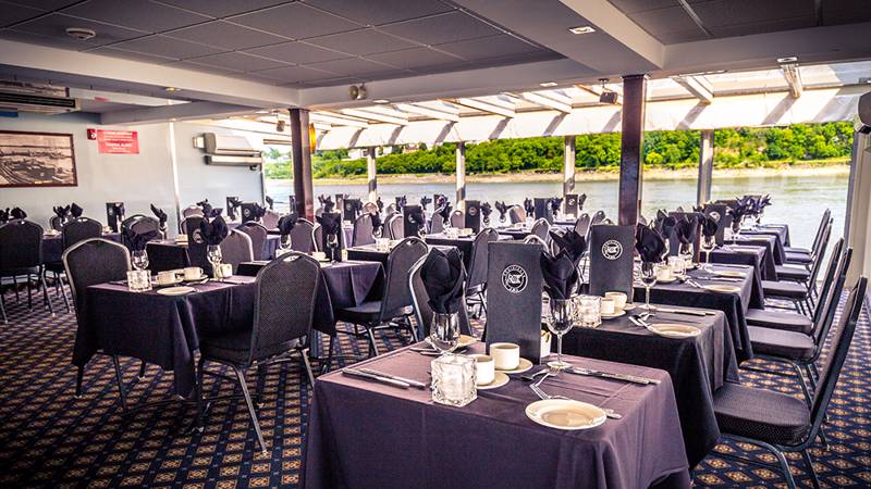 Une salle de restaurant du navire AML Louis Jolliet avec des tables dressées et une vue imprenable sur le fleuve Saint-Laurent à Québec