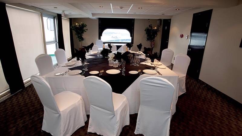 Salon du capitaine avec une table et des chaises dressées de façon chic à bord du navire AML Louis Jolliet à Québec. 