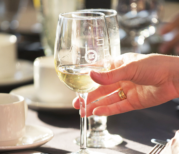 Une main tenant un verre de vin blanc frais en gros plan.