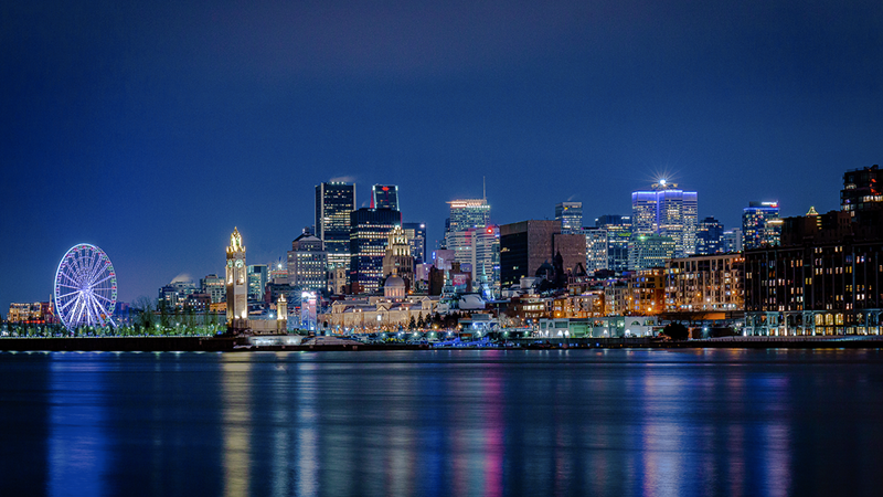 Une vue nocturne sur la skyline illuminée de Montréal depuis le Vieux Port et la grande roue.