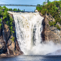 Chute Montmorency en été se jetant dans la rivière Montmorency en contrebas, entourée d'arbres avec une passerelle suspendue au-dessus