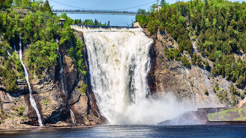 Chute Montmorency en été se jetant dans la rivière Montmorency en contrebas, entourée d'arbres avec une passerelle suspendue au-dessus
