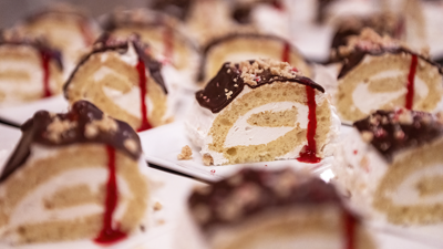 Délicieuses petites bûches avec une garniture de crème, avec de la sauce au chocolat et aux framboises sur le dessus, saupoudrées de noix concassées, prêtes à être servies. 