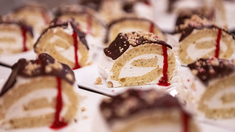 Délicieuses petites bûches avec une garniture de crème, avec de la sauce au chocolat et aux framboises sur le dessus, saupoudrées de noix concassées, prêtes à être servies. 