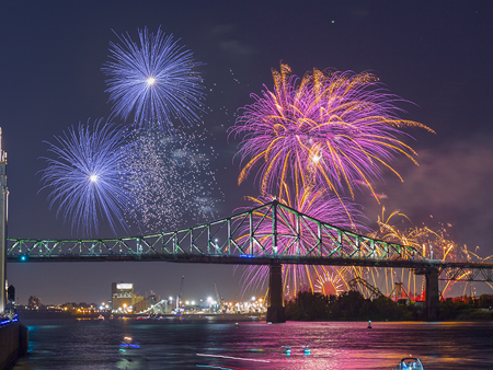 Vue sur la tour de l'horloge et le pont Jacques Cartier à Montréal avec des feux d'artifice surplombant les monuments