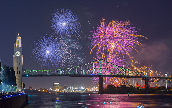 Vue sur la tour de l'horloge et le pont Jacques Cartier à Montréal avec des feux d'artifice surplombant les monuments