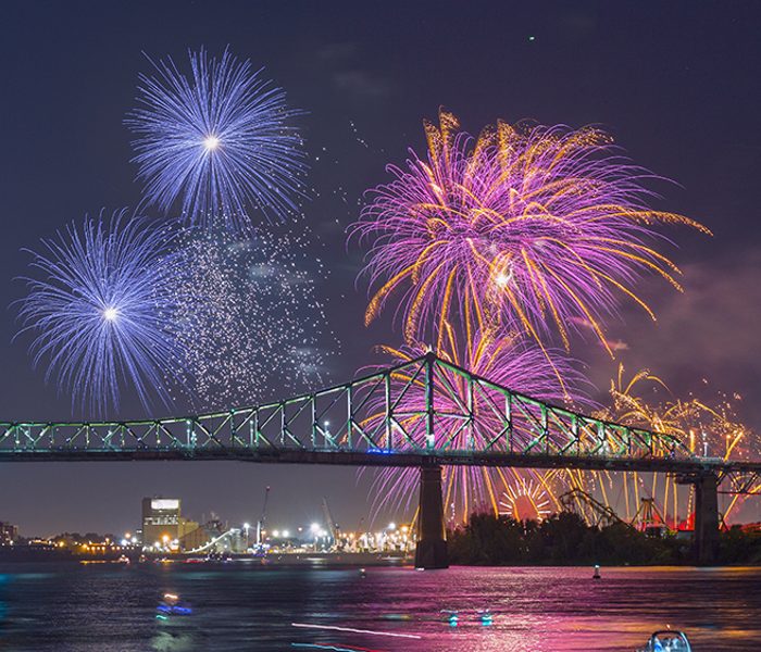 Vue sur la tour de l'horloge et le pont Jacques Cartier à Montréal avec des feux d'artifice surplombant les monuments