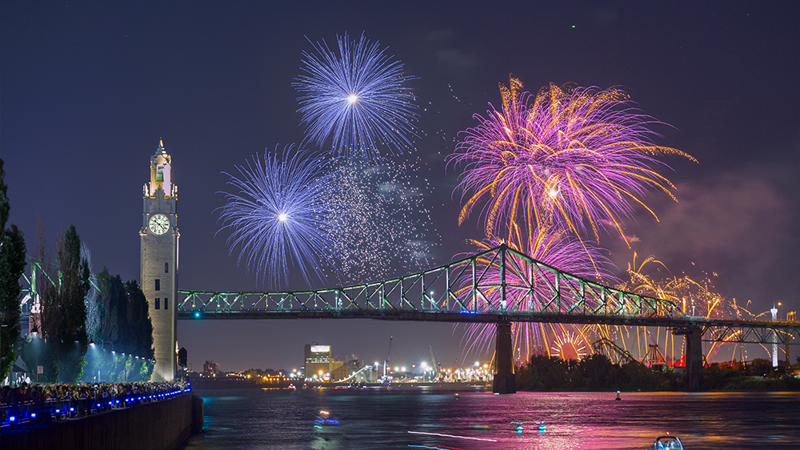 Vue sur la tour de l'horloge et le pont Jacques Cartier à Montréal avec des feux d'artifice surplombant les monuments